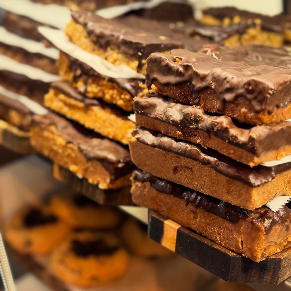 Stacked chocolate-coated pastries with golden, crumbly layers displayed on a dessert tray.
