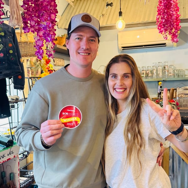 A man and woman smiling, holding a "BOBAWARDS Winner 2025" sticker in a vibrant shop.