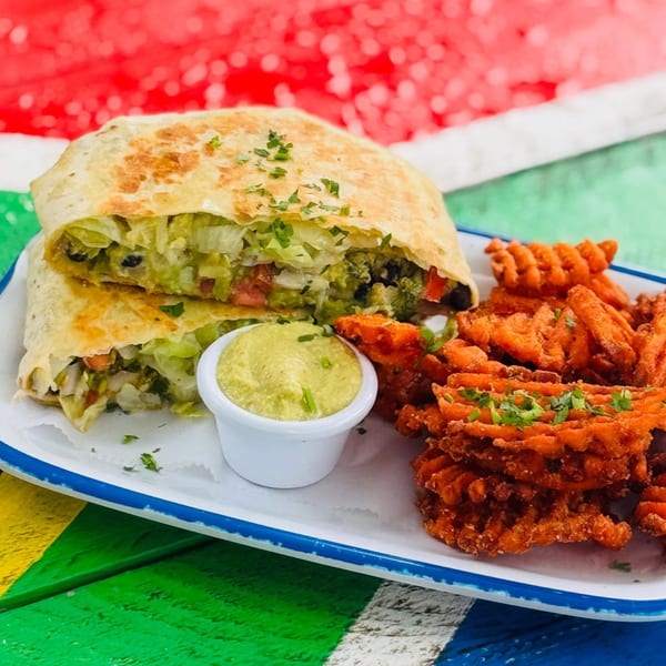 A quesadilla with lettuce, tomato, and black beans, served with waffle fries and guacamole.