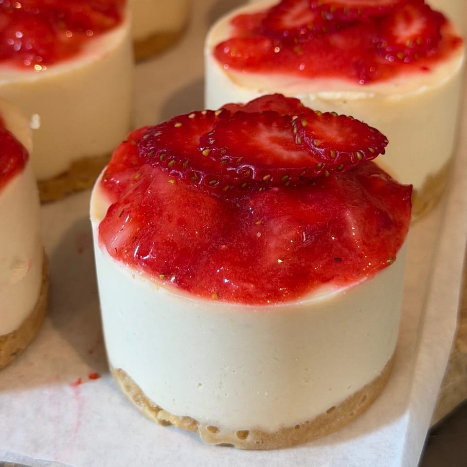 Close-up of creamy berry-topped desserts in small pastry cups, garnished with fresh sliced strawberries.